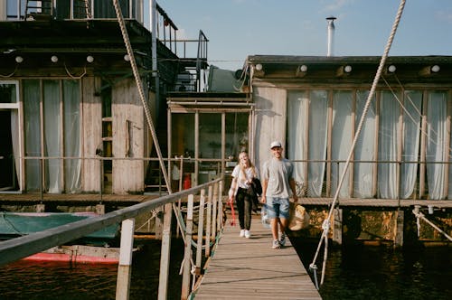 Photo of a Man and a Woman Walking on a Wooden Boardwalk