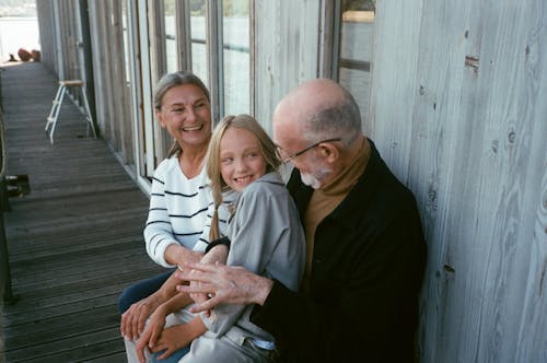 Free A Child Sitting on an Elderly Man's Lap Sitting Beside an Elderly Woman Stock Photo