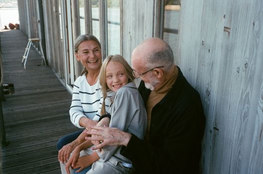 A Child Sitting on an Elderly Man's Lap Sitting Beside an Elderly Woman