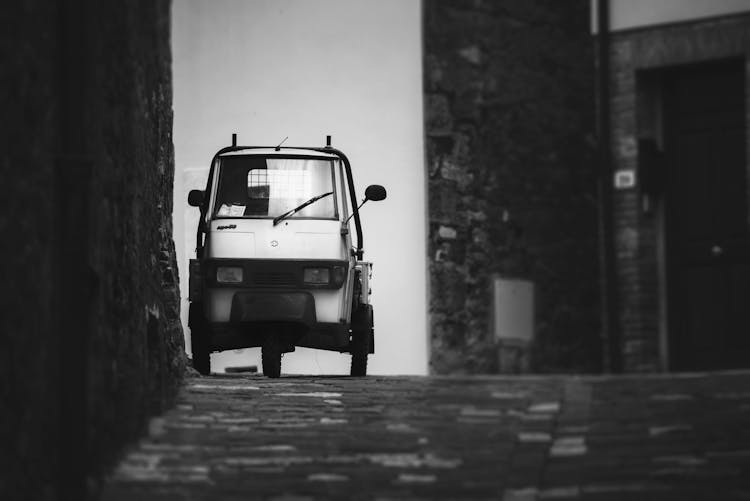 Black And White Photo Of Piaggio Ape Parked On A Street