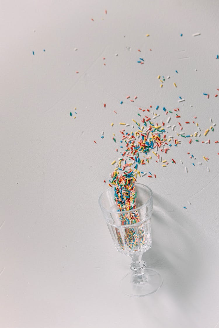 Colorful Sugar Sprinkles Spilling From A Wine Glass