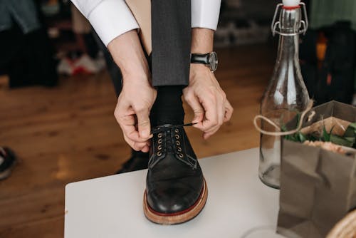 Close-Up Photo of a Person Tying His Black Shoelaces