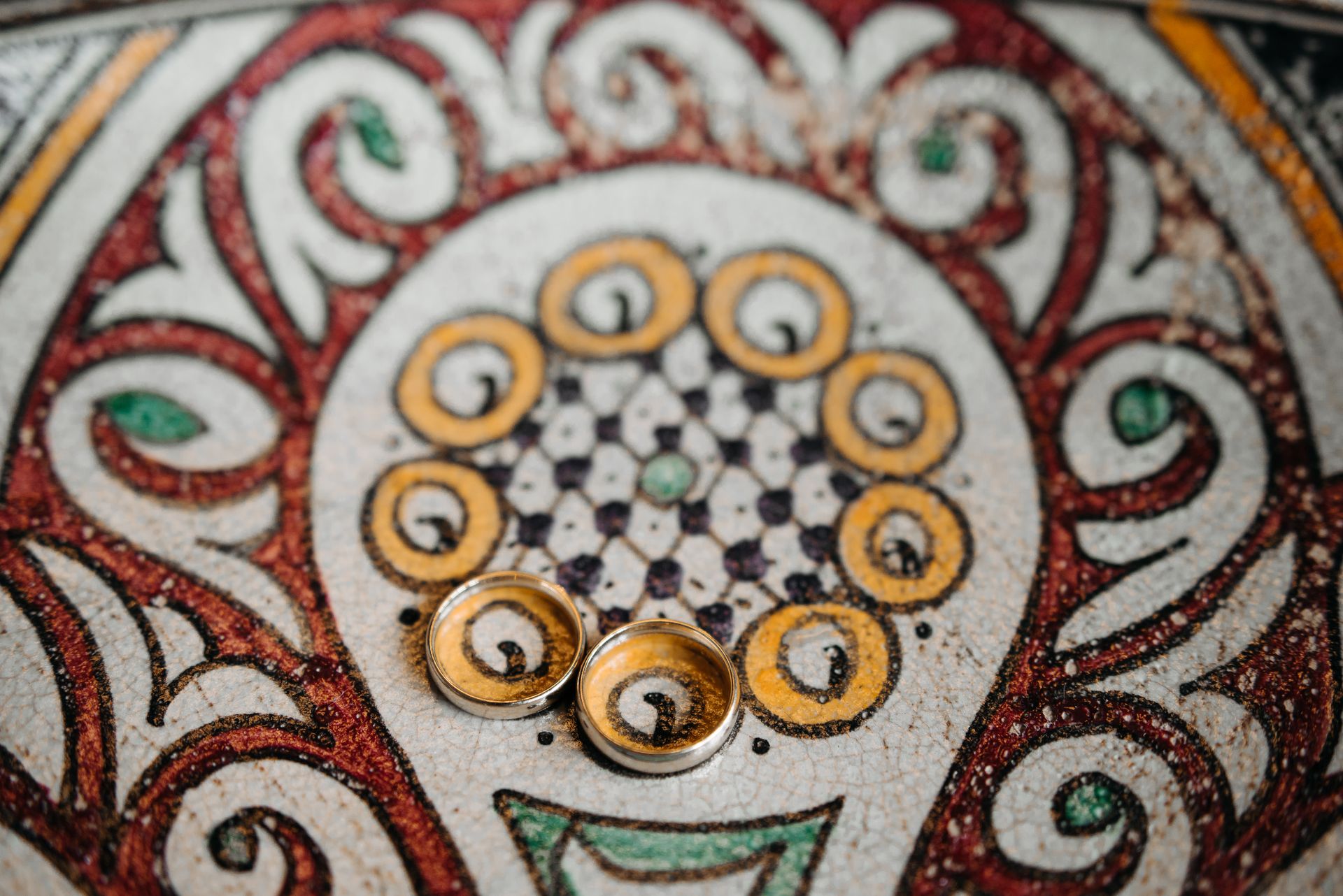 Elegant gold rings resting on an ornate mosaic pattern, exuding a touch of luxury and creativity.