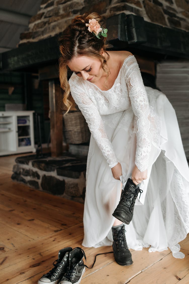 Woman In A White Dress Putting On Her Black Boots