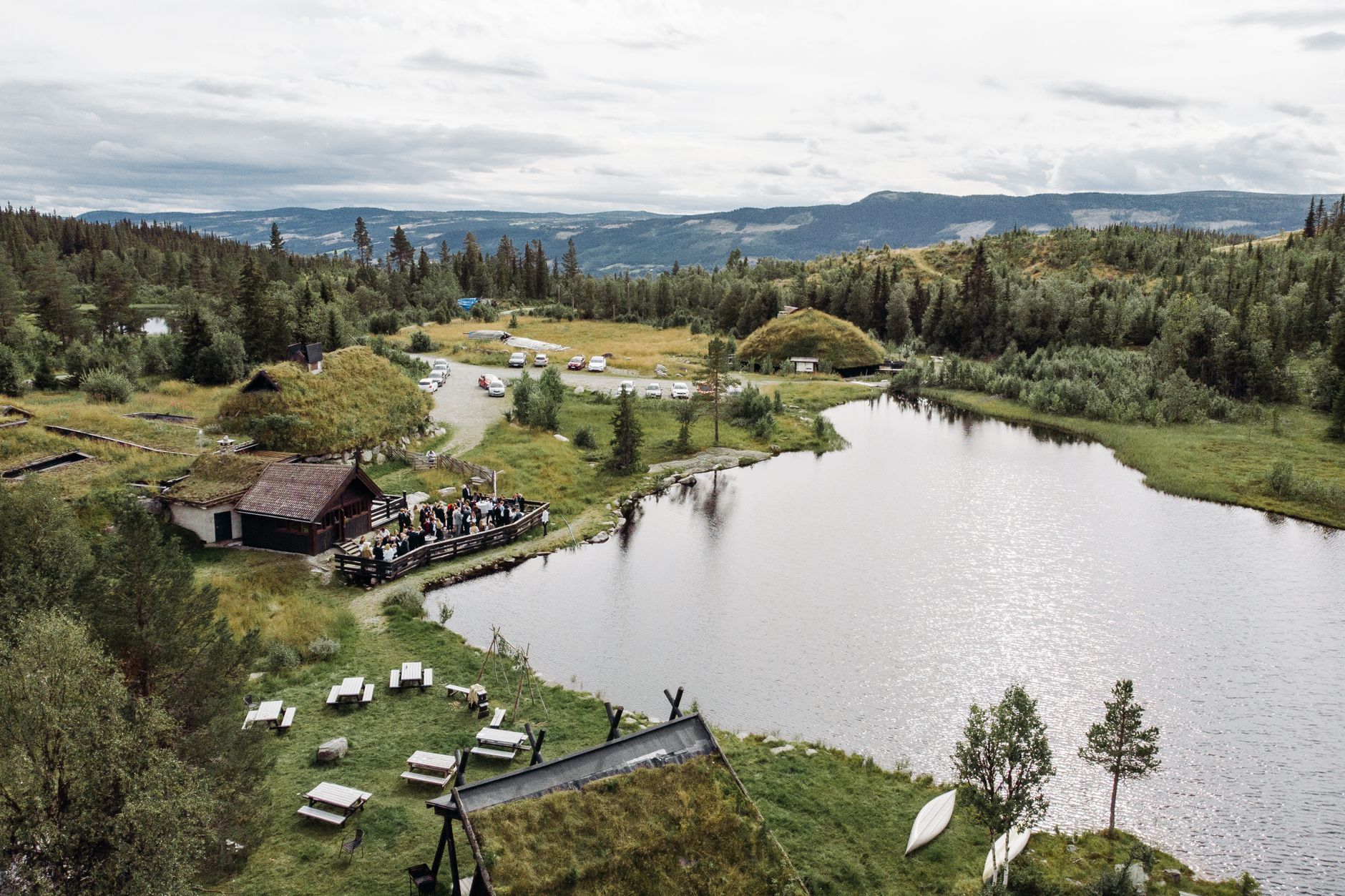 Aerial scene of a serene lake and a gathering near a wooden house in Hemsedal, Norway.
