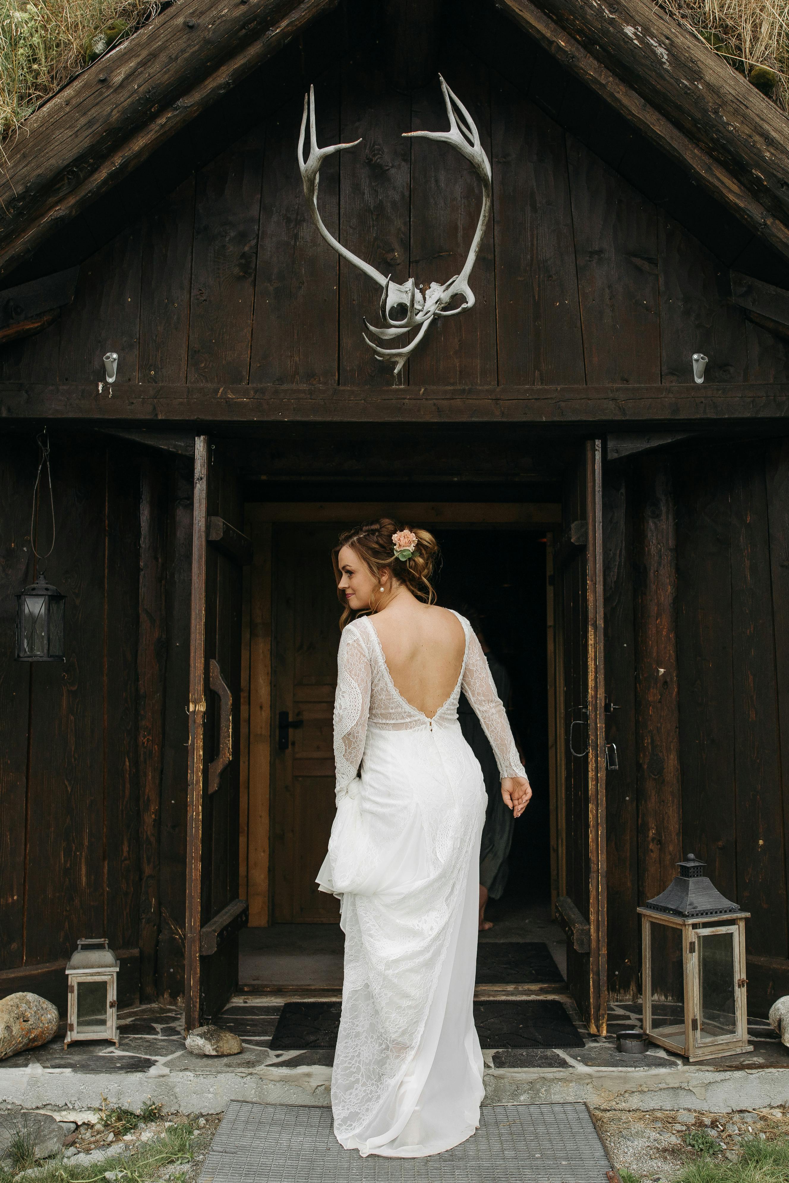 grátis Mulher Em Vestido De Noiva De Mangas Compridas Entrando Em Uma Porta De Madeira Aberta Foto profissional