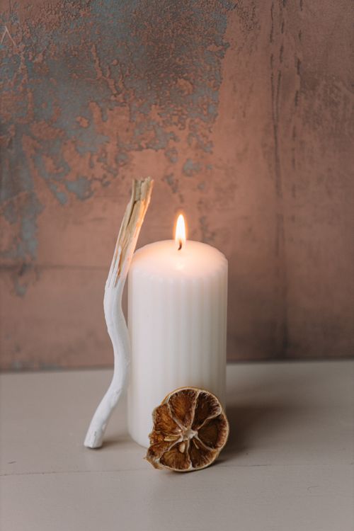 Free Warm and inviting still life of a lit candle with dried lemon and wooden stick on rustic surface. Stock Photo