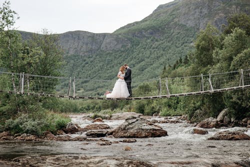 Couple Standing on Bridge Above a River