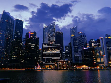 A mesmerizing view of Singapore's skyline illuminated at dusk, reflecting on the water.
