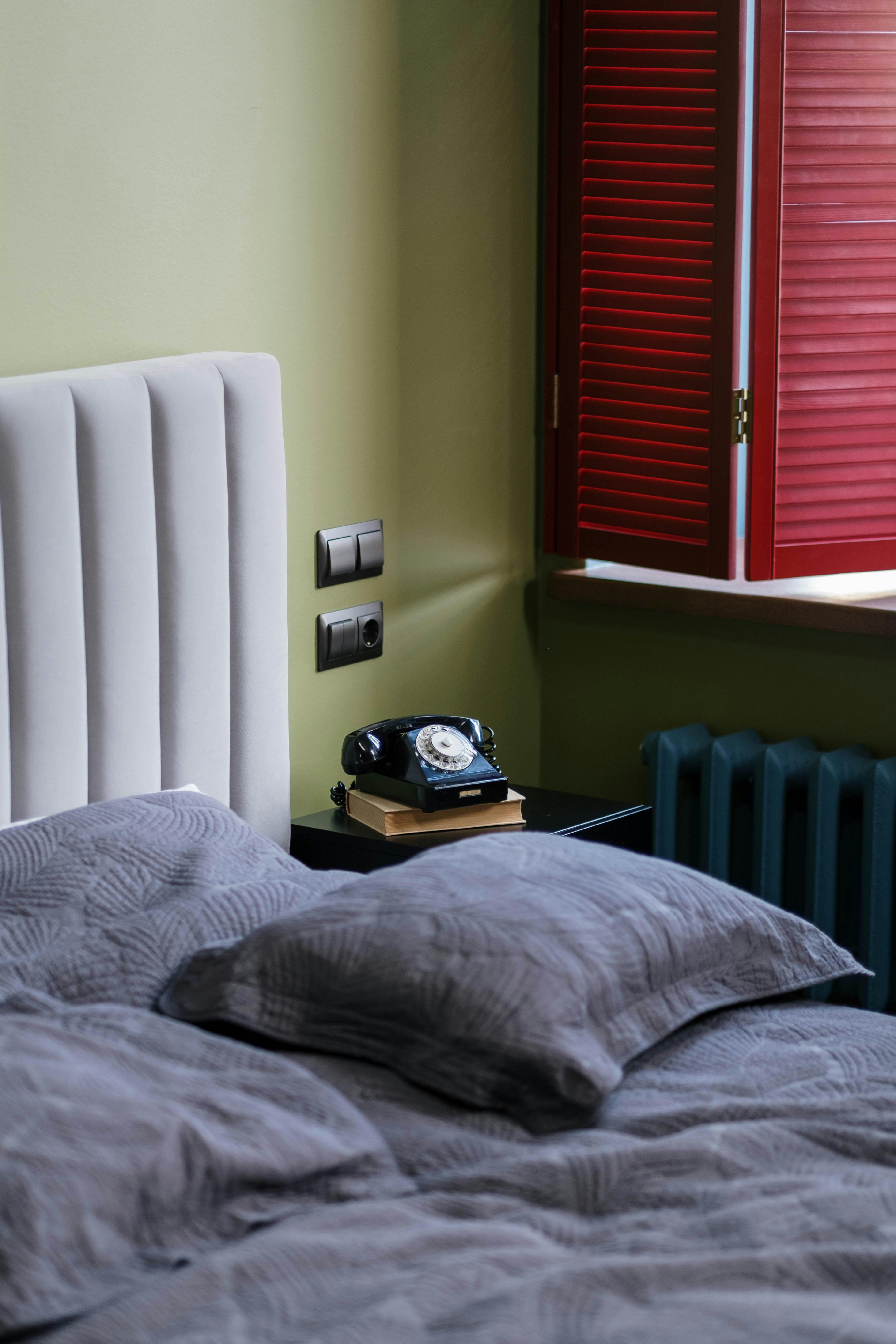 Cozy bedroom interior featuring a retro rotary telephone on a nightstand.
