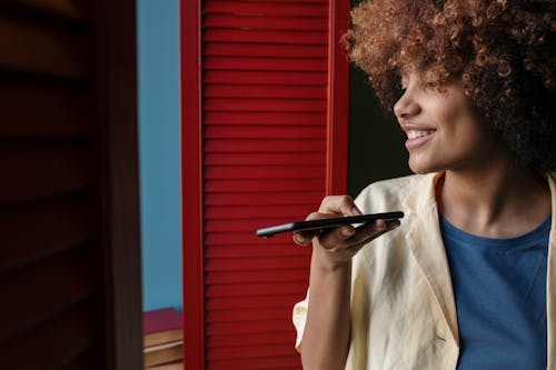 A Woman with Curly Hair Smiling While Talking on the Phone