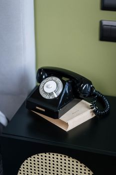 A nostalgic black rotary dial telephone on a desk, evoking retro style.