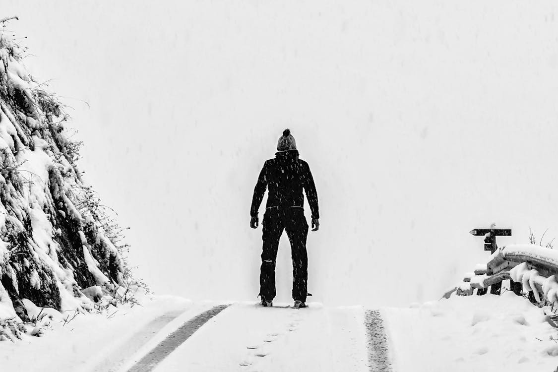 Hombre De Pie Sobre Un Suelo Cubierto De Nieve Blanca Junto A La Montaña