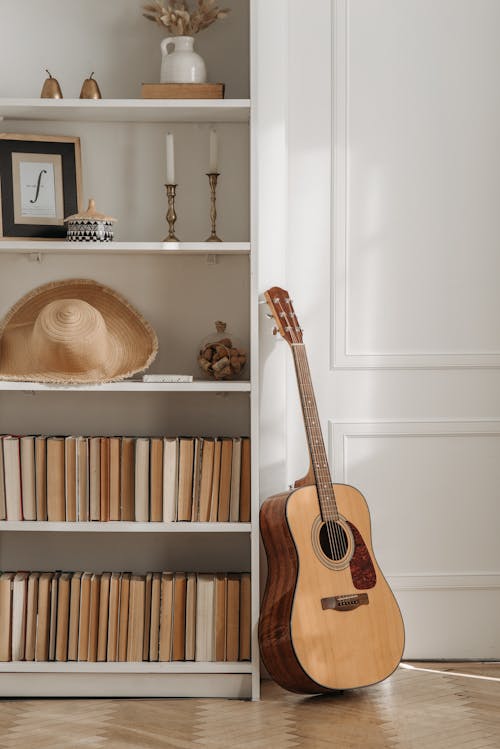 Brown Acoustic Guitar Beside a Bookcase