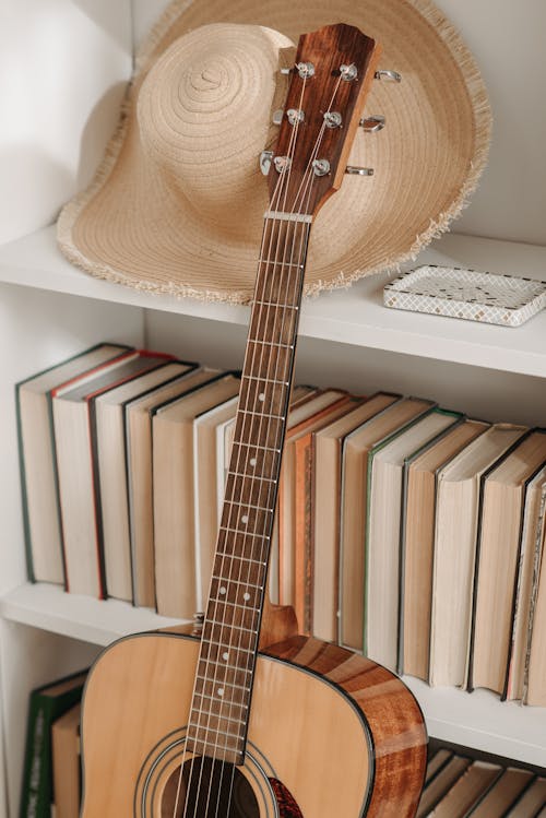An Acoustic Guitar beside a Bookshelf