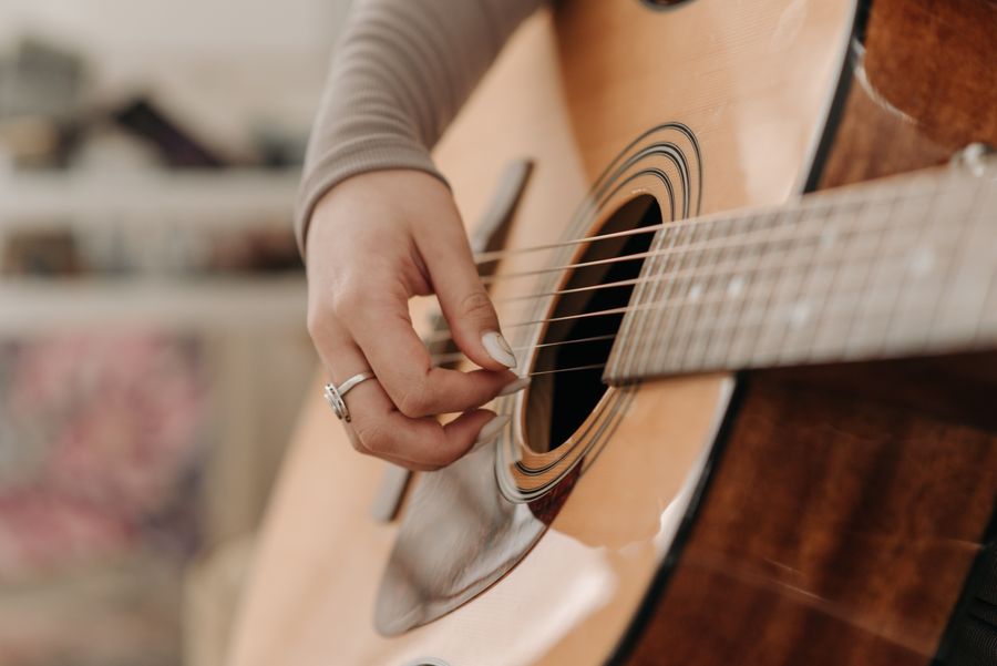 Hands fingerpicking an acoustic guitar in a studio, photo by Pavel Danilyuk on Pexels