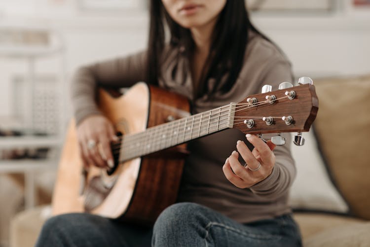 Woman Tuning A Guitar