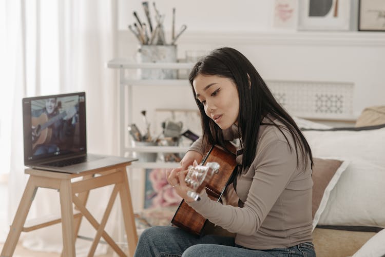 Woman Learning How To Play A Guitar