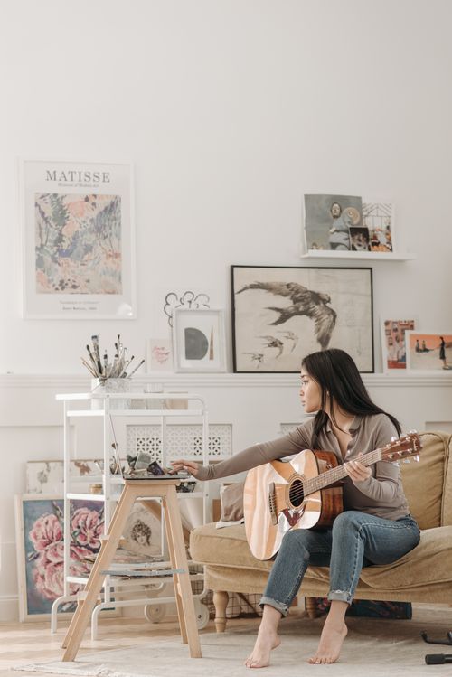 Free Young woman learning guitar in a cozy, artistic home setting. Stock Photo