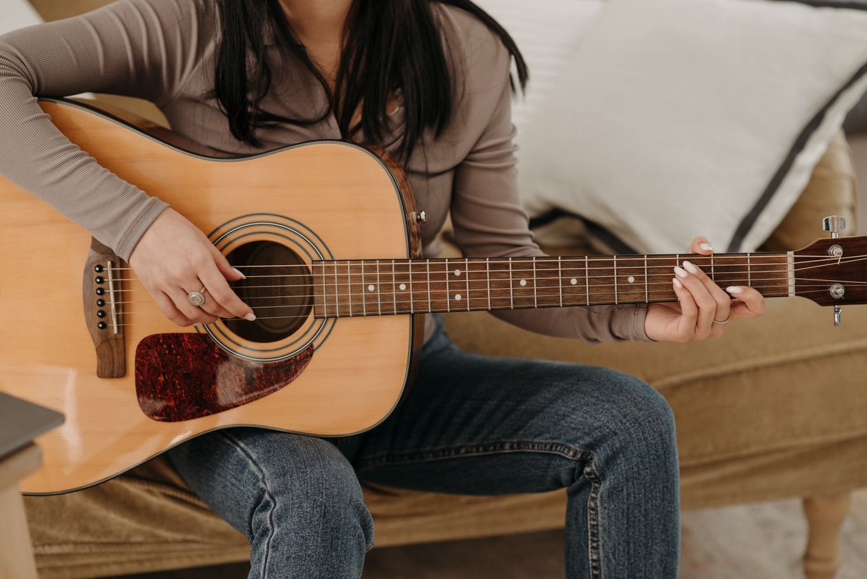 Musician practicing acoustic guitar in a softly lit room