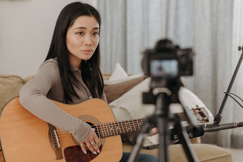 Free Woman Looking on Digital Camera Holding Guitar Stock Photo