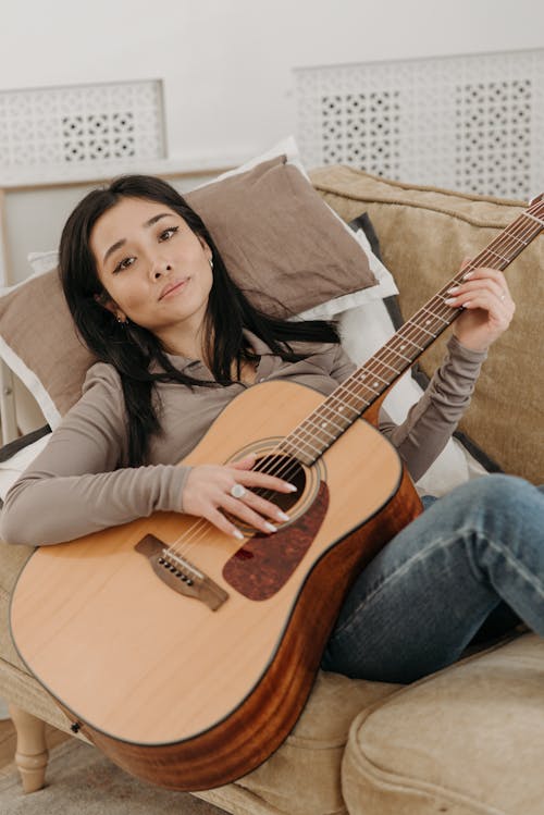 Free A Woman in Brown Long Sleeves Playing Acoustic Guitar Stock Photo