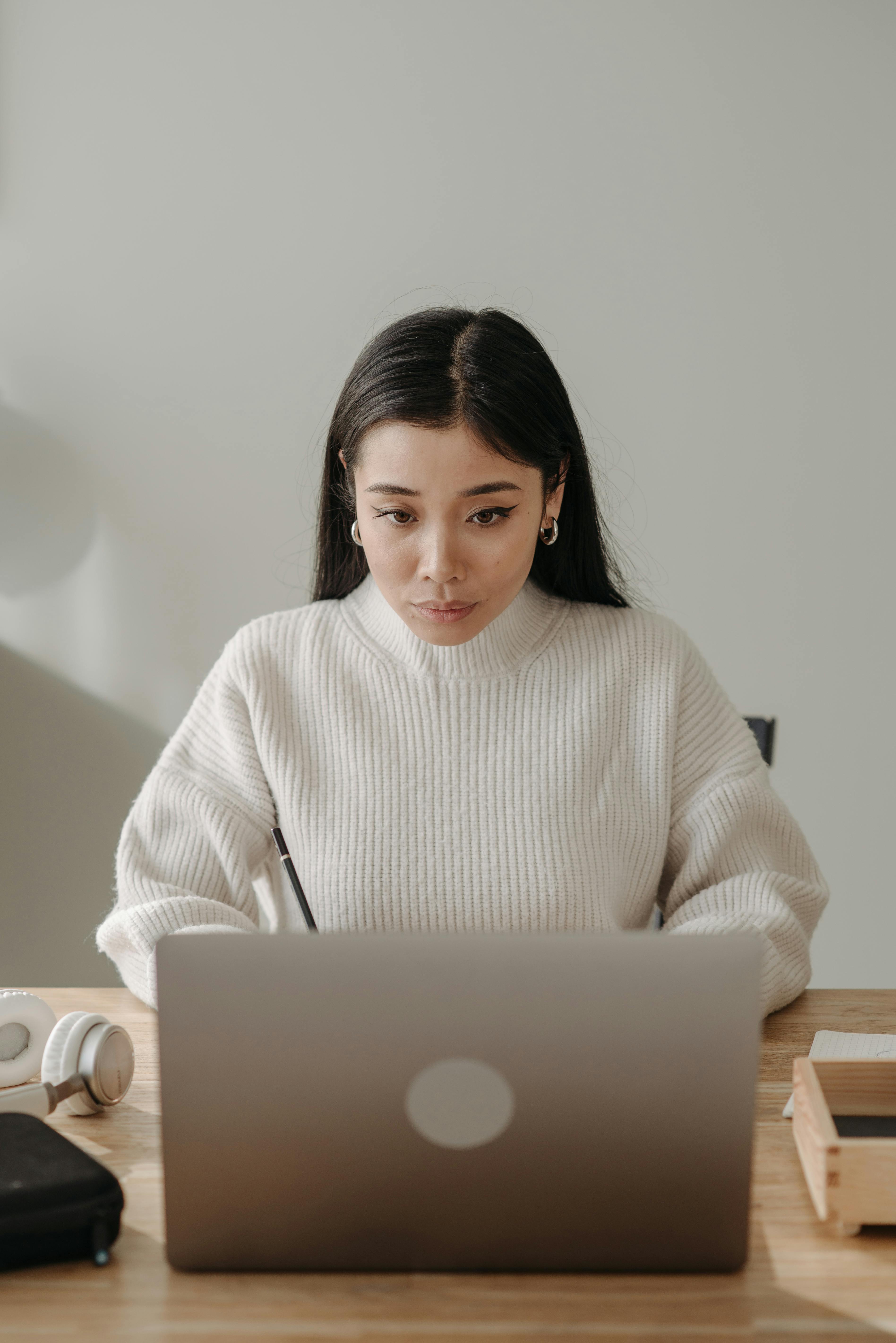 woman in white turtleneck sweater using silver macbook