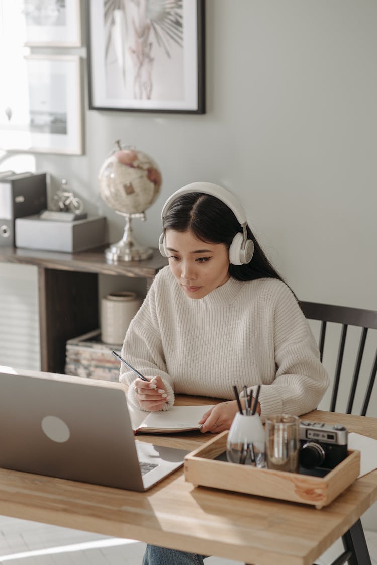 A Woman Using A Laptop And A Headphones