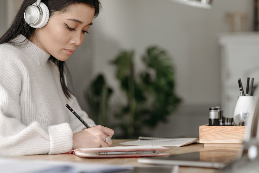Learner writing at a desk while using digital study tools