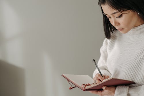 Close-Up Photography of a Woman Writing on Notebook