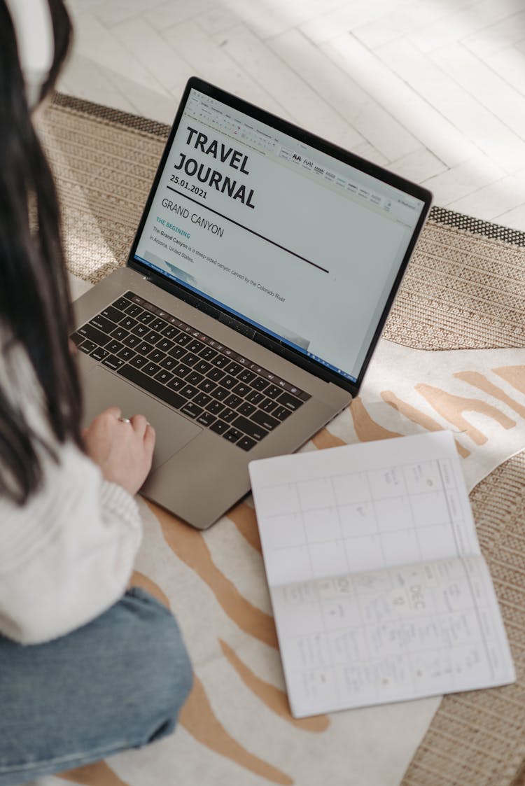 A Woman Composing A Travel Journal With  A Laptop