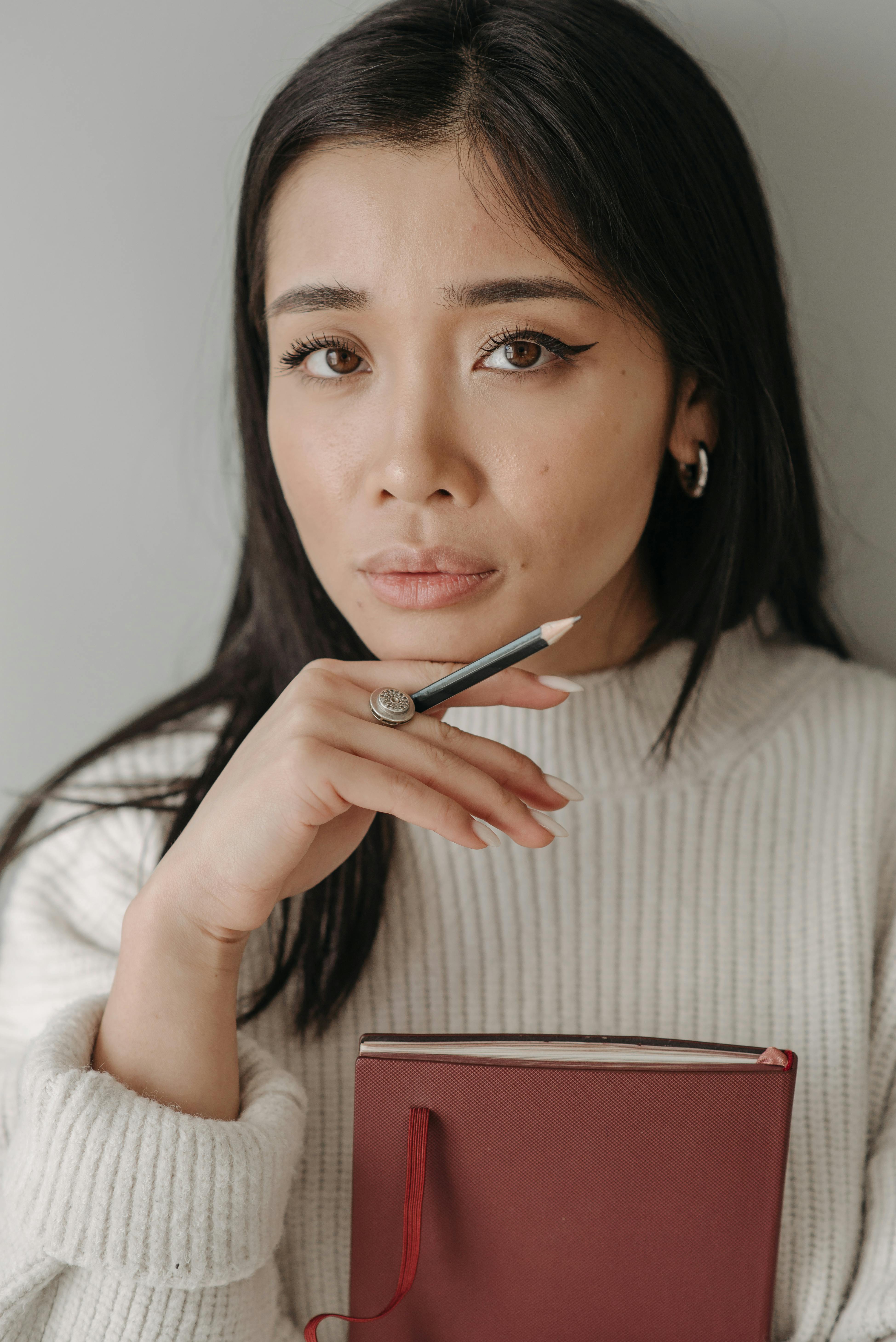 a woman holding a pen with her hand on chin