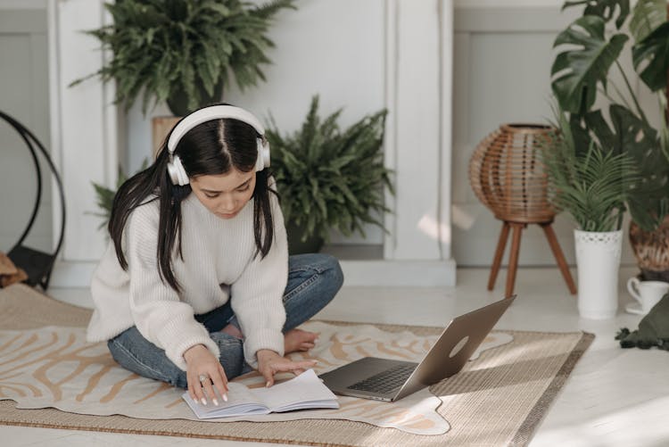 Woman On Head Phones Sitting Crossed Legged On Carpet