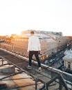 Man in White Long Sleeve Shirt and Black Pants Standing on Top of a Building during
