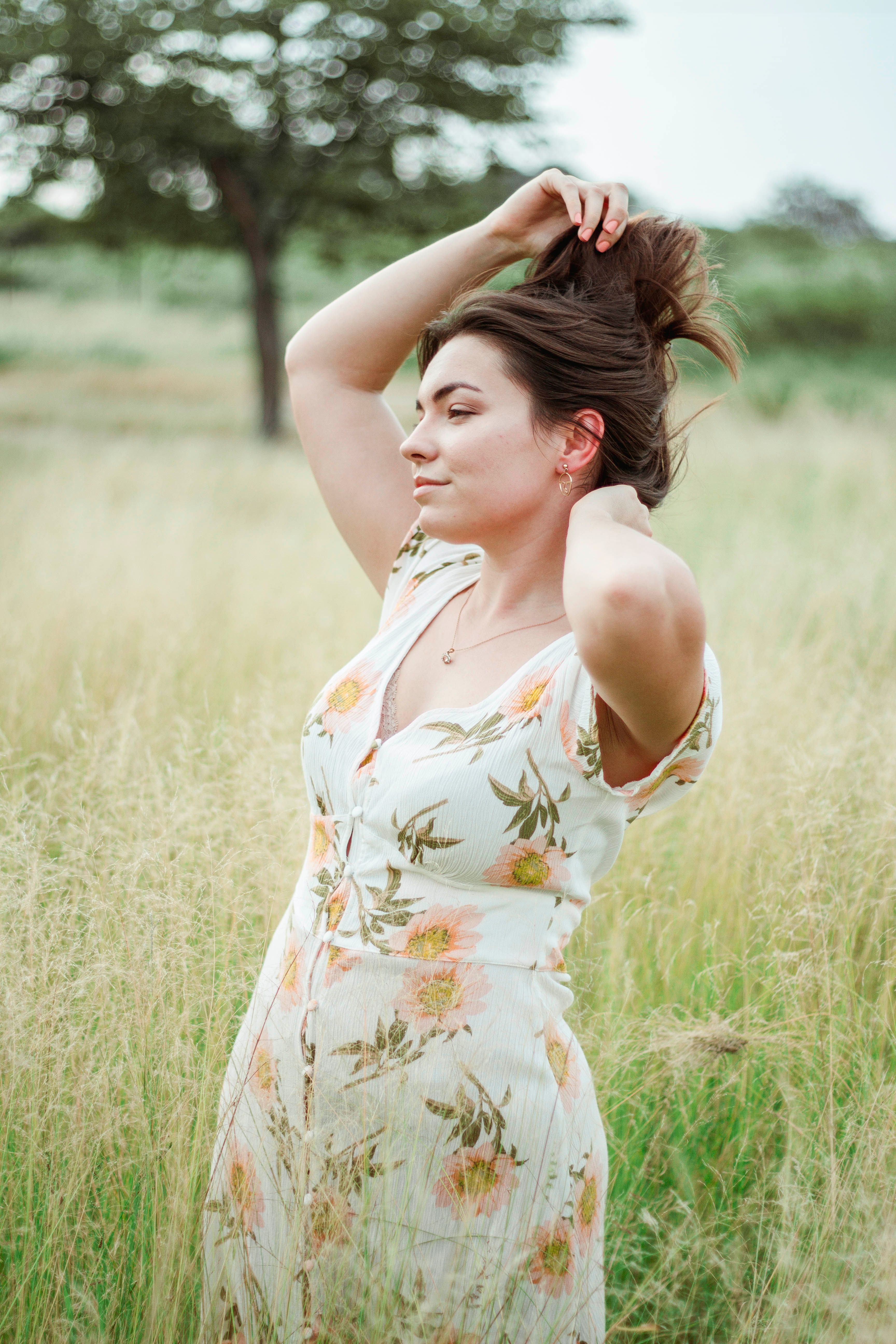 A Woman in Flora Dress Standing on Green Grass Field · Free Stock Photo