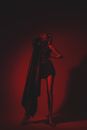 Anonymous woman in stylish outfit in studio with red lights