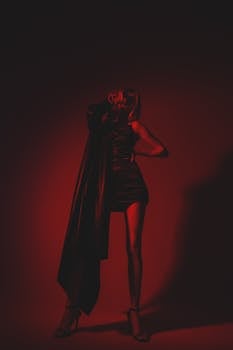 Fashionable woman in a dramatic red-lit studio portrait showcasing modern style.