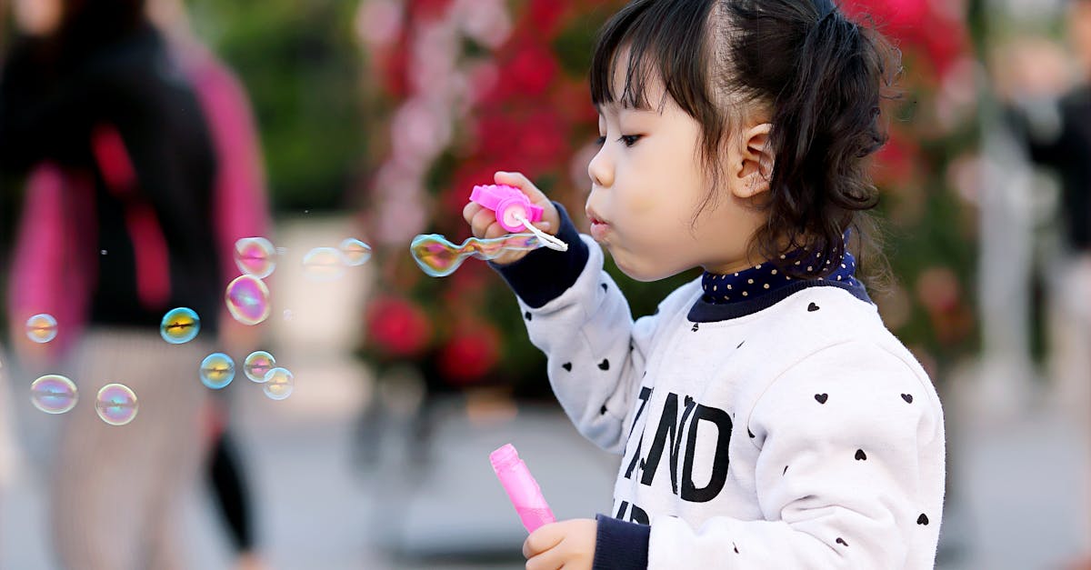 Toddler Girl Wearing White and Black Sweater Holding Plastic Bottle of Bubbles at Daytime