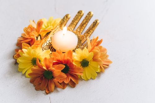 Free A close-up of a lit candle surrounded by vibrant orange and yellow flowers, symbolizing the Diwali festival of lights. Stock Photo