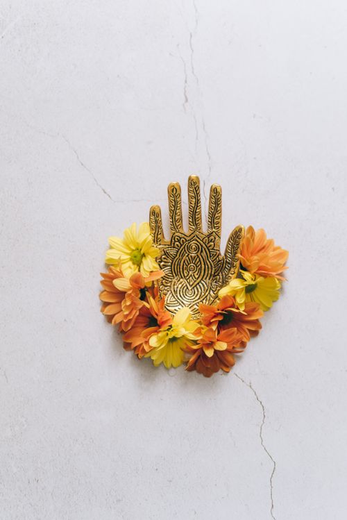 Free A gold hand sculpture adorned with colorful flowers, ideal for festive decor. Stock Photo