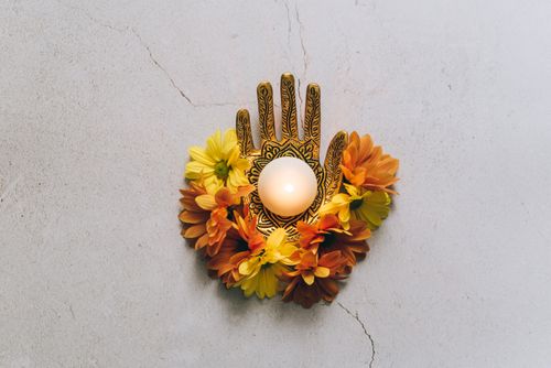 Free Artistic floral candle holder with orange and yellow flowers on a cracked stone surface. Stock Photo