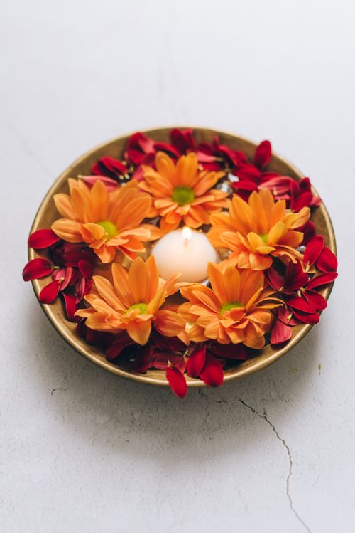 Free A serene candle arrangement with vibrant orange flowers and red petals on a gray surface, perfect for festive decor. Stock Photo