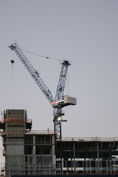 High-rise building under construction with a prominent tower crane during the day.