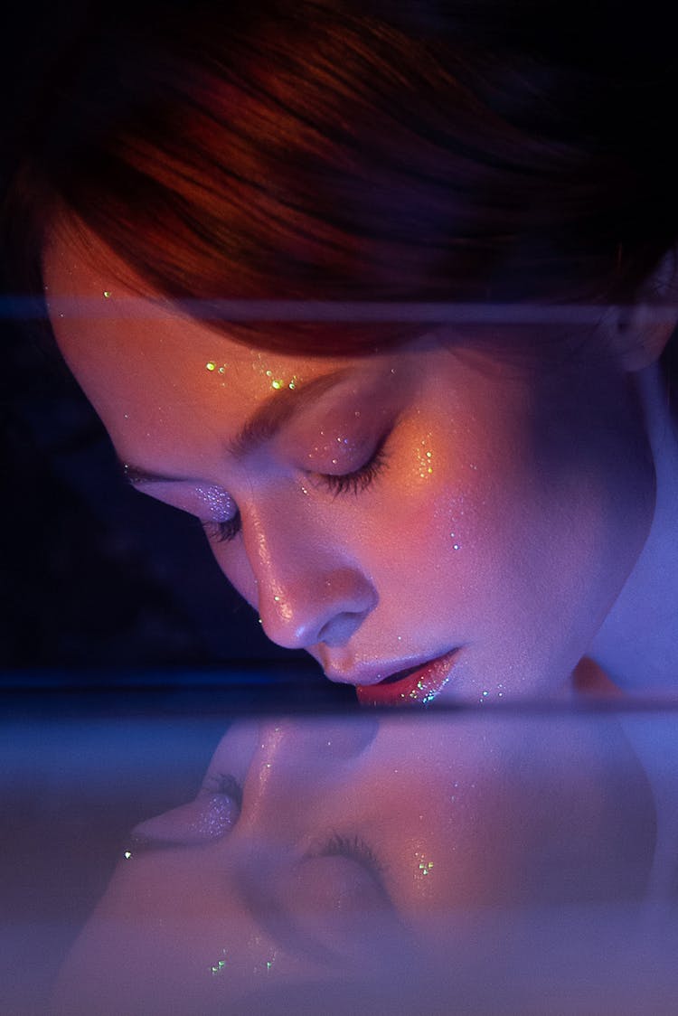 Thoughtful Female Put Face In Glass Container With Water