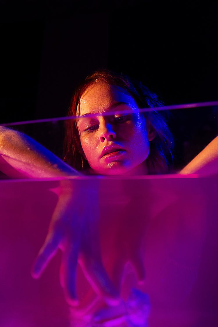 Thoughtful Woman With Hands In Glass Container With Purple Liquid