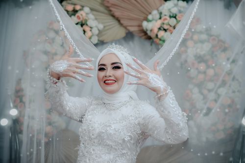 Free Bride in white with intricate henna and floral backdrop, capturing joy and elegance. Stock Photo