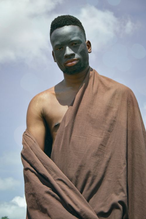 Free Captivating portrait of a man with painted face wrapped in brown fabric under a clear sky. Stock Photo