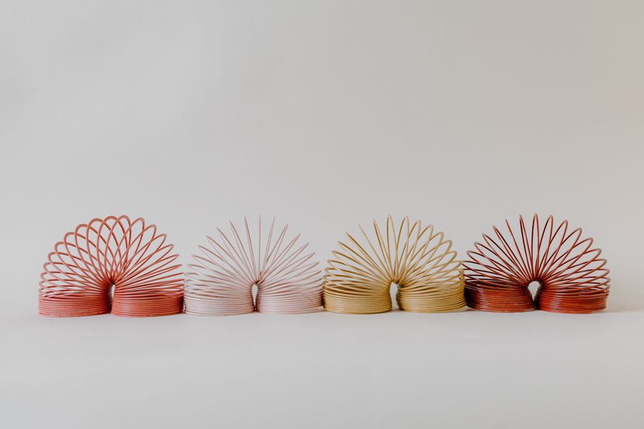 A row of colorful slinkies displayed on a neutral background, perfect for creative designs.
