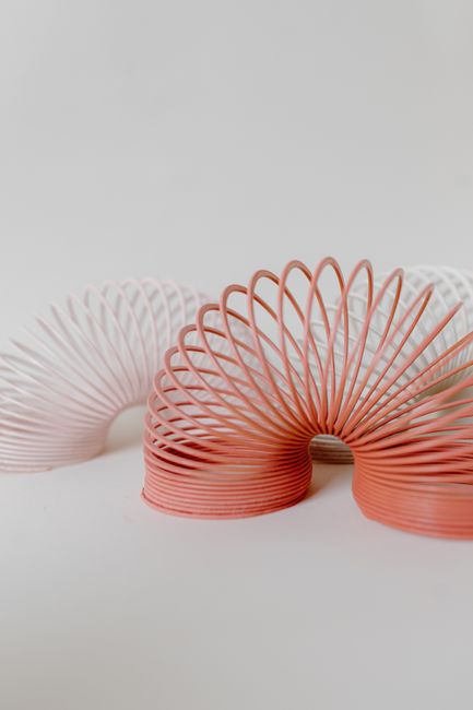 Close-up of pastel-colored slinkies creating artistic curves on a white background.
