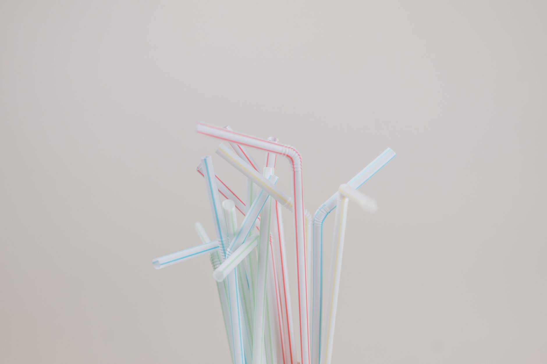 Aesthetic arrangement of colorful plastic straws on a neutral backdrop.